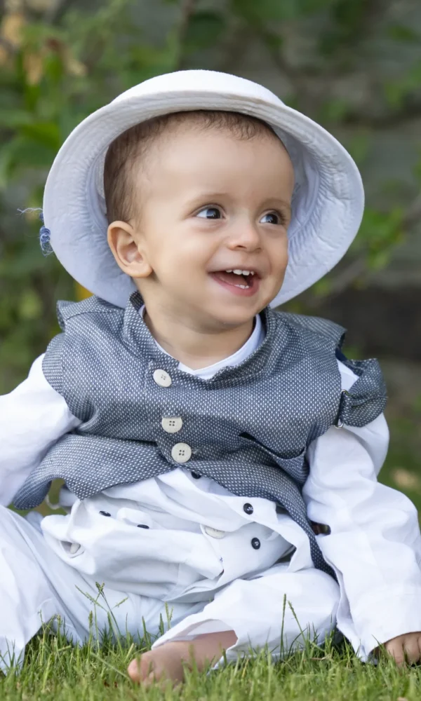 αγοράκι με καπέλο καθισμένος στο χορτάρι