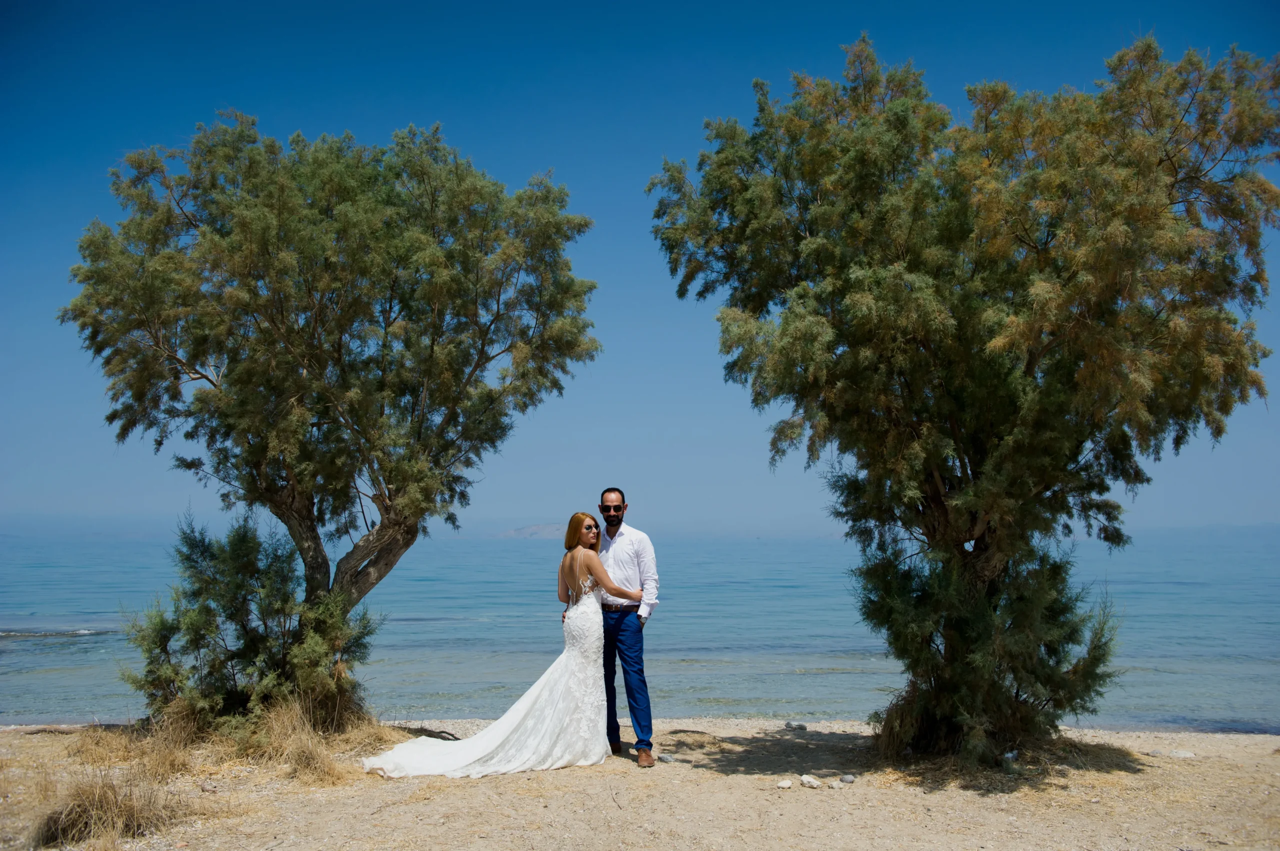 ζευγάρι αγκαλιασμένο ανάμεσα σε δύο δέντρα