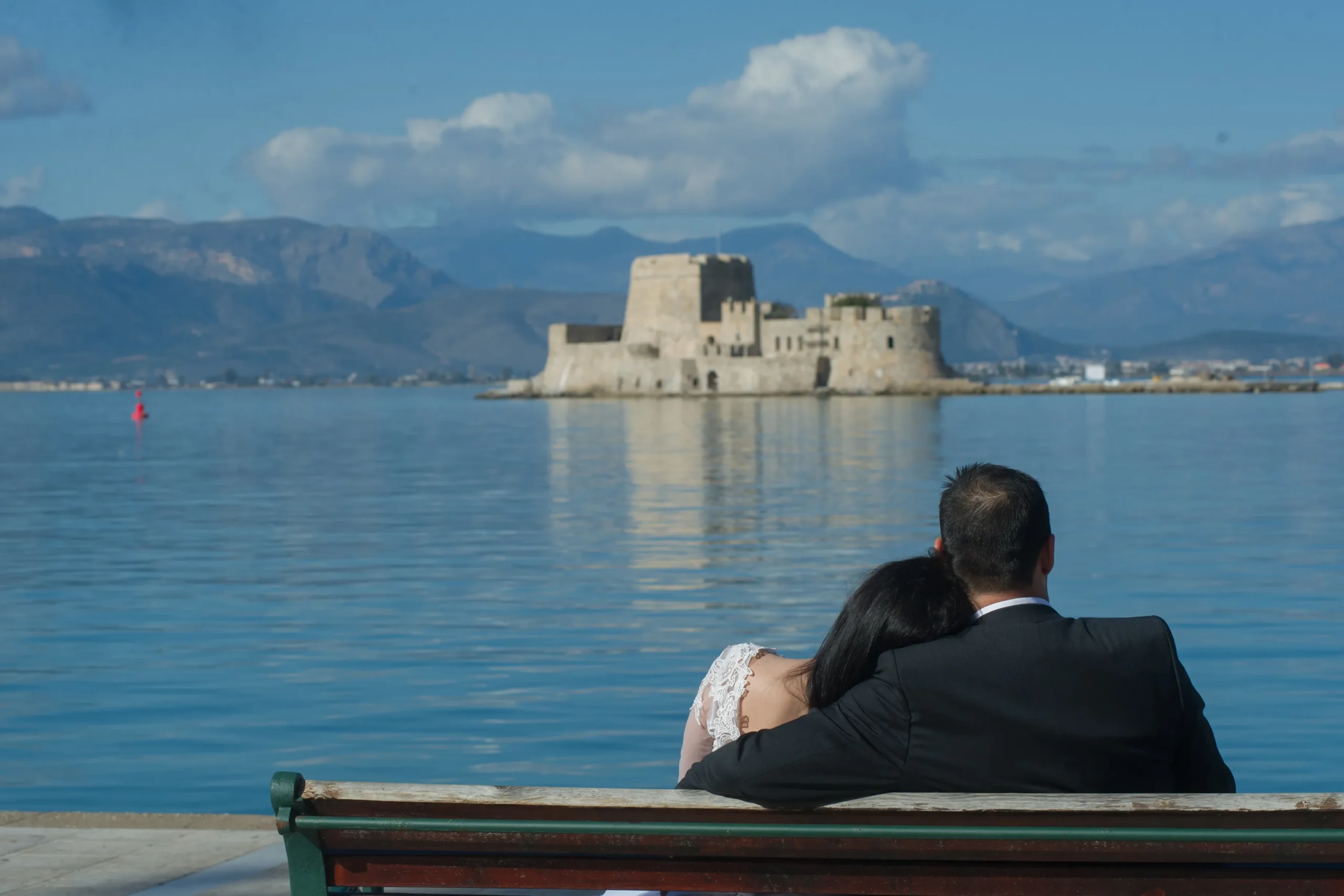 νύφη και γαμπρός καθισμένοι σε παγκάκι με φόντο το Μπούρτζι